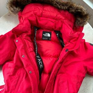 red mid length north face parka with faux fur hood